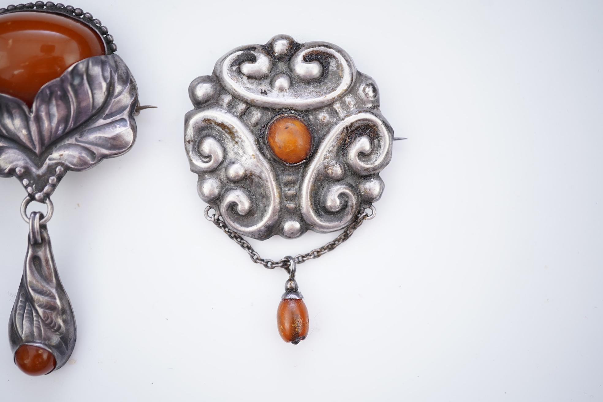 Two Arts & Crafts silver and amber pendant brooches, probably Denmark, early 20th century
